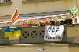 A Barceloneta neighborhood flag, a Estelada (Catalonian) flag, and an anti-tourism banner that reads 